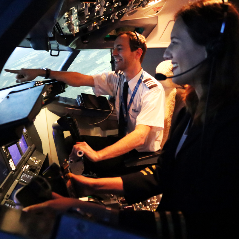 A woman enjoying a corporate event involving learning how to control a flight simulator.