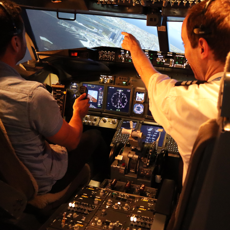 A person uses the controls of a flight simulator to prepare for landing.