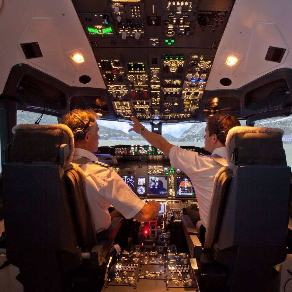 Two pilots in a multi-crew cooperation (MCC) course work together to control a flight simulator aeroplane.