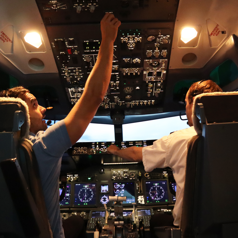 A pilot controls the dials inside of the cockpit of a realistic flight simulator.