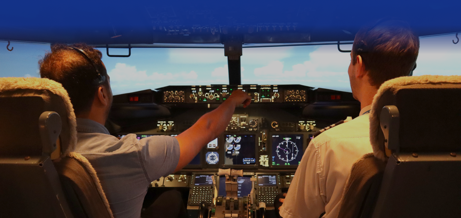 Two pilots sitting in the cockpit of a boeing 737 simulator while one of them handles the controls.